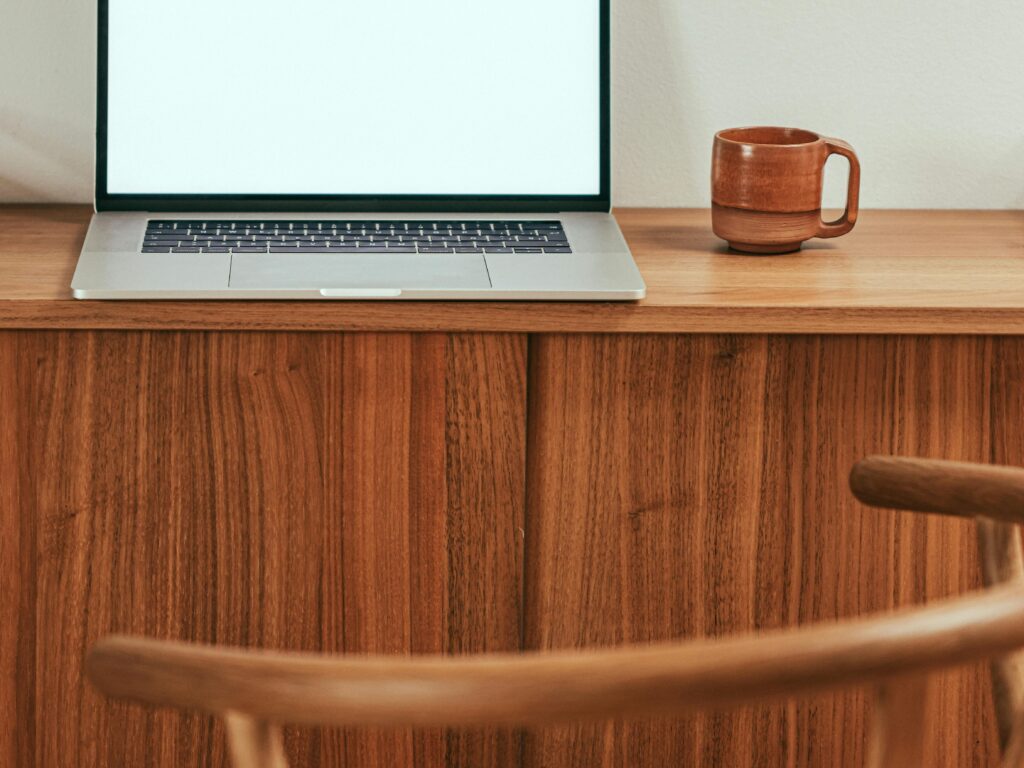 A modern minimalist workspace featuring a laptop with a blank screen and a coffee mug on a wooden table.